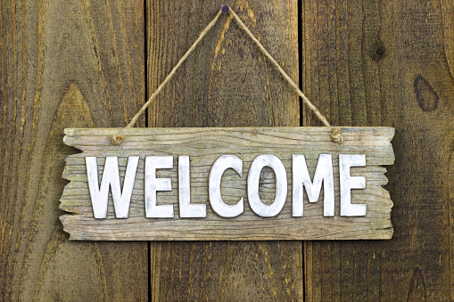 Wood welcome sign hanging on rustic wooden background