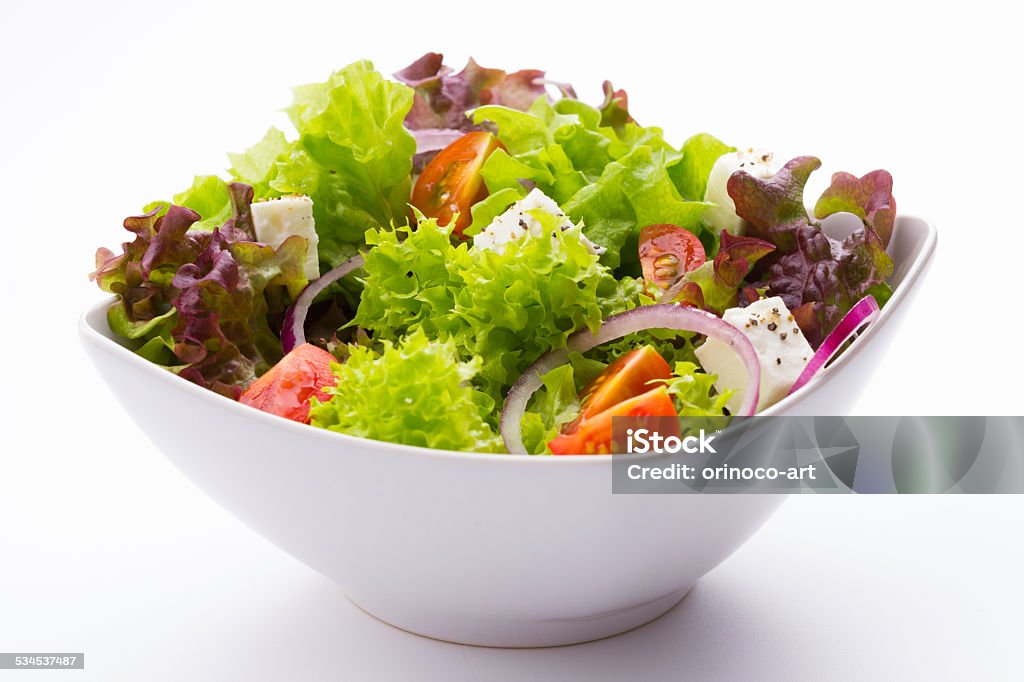 mixed vegetable salad with tomatoes and feta cheese mixed vegetable salad with tomatoes, onions and feta cheese in a white bowl on white background 2015 Stock Photo