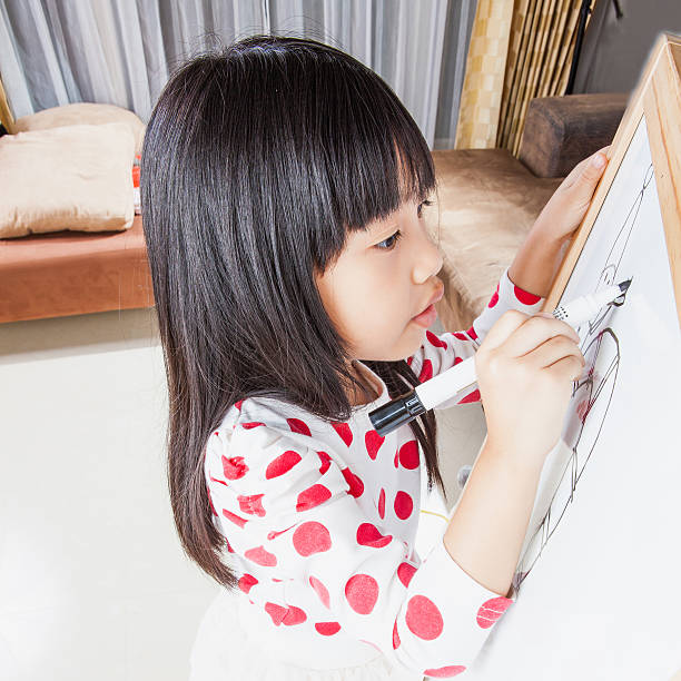 istock Kid girl writes on white board with black mark pen. 534539113