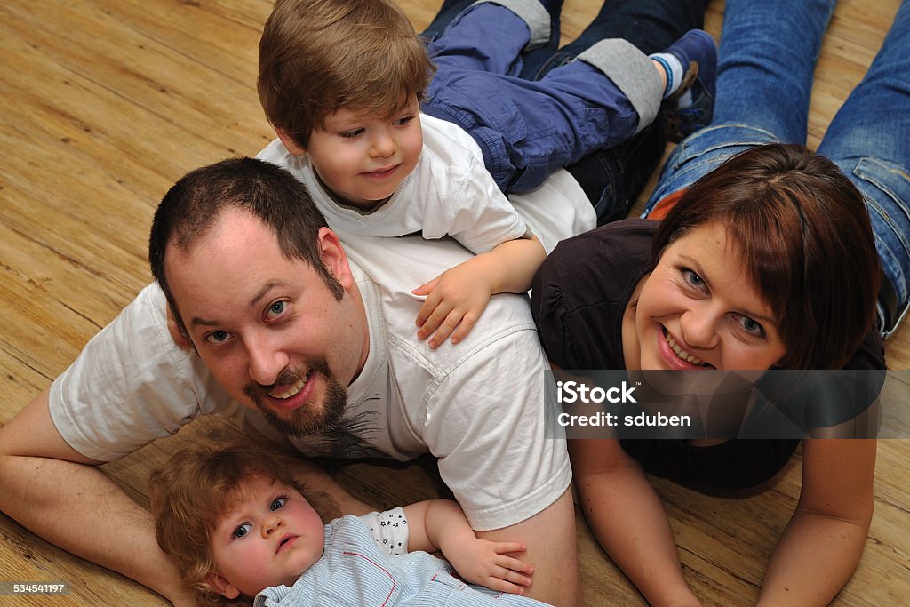 Portrait of happy family at home Portrait of happy family lying on wooden floor at home Adult Stock Photo