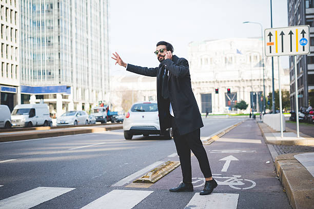 Young handsome bearded contemporary businessman asking taxi stock photo