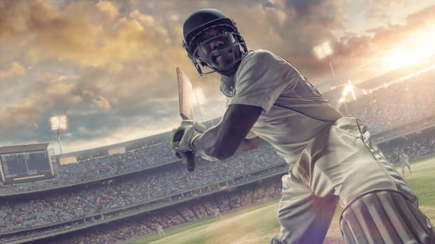 Cricket Batsman About to Hit Ball During Outdoor Cricket Match A close up image of a professional male cricket batsman in mid action holding his bat behind him, about to strike the cricket ball. The action occurs during a cricket match in an outdoor cricket pitch in a generic floodlit stadium full of spectators under a dramatic evening sky at sunset.  test cricket stock pictures, royalty-free photos & images