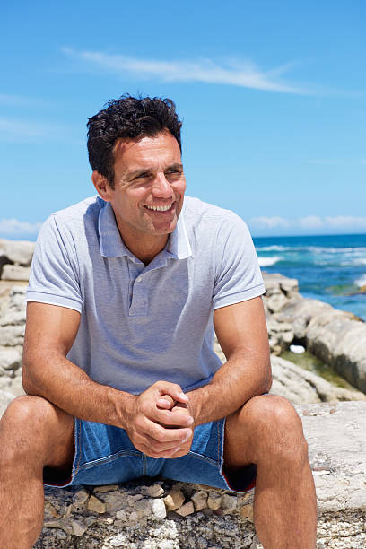 istock Smiling middle aged man sitting by the beach 534548014