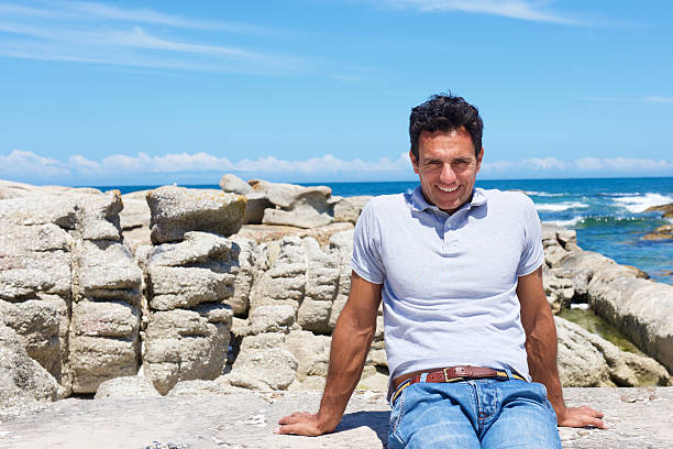 istock Smiling older man sitting at the beach 534548892