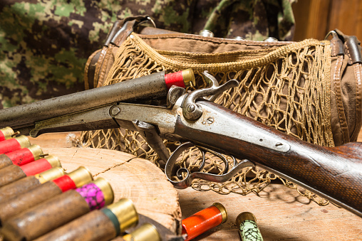 Still life.Vintage shutgun and hunting equipment (hunting knife, hunting horn, hunting belt for cartridges, hunting bag on a wooden background