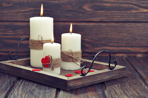 Candles on  vintage tray with fabric hearts  on wooden background