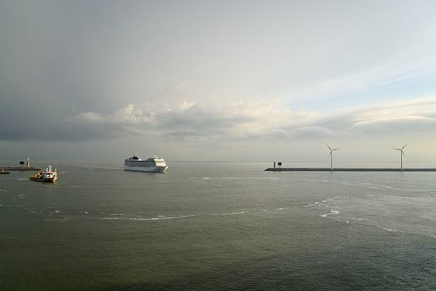 INSP: Too much cruise ship?  A cruise ship, the MSC Musica, sails into Zeebrugge harbor early in the morning while the Sebastian Cabot, a dredger, is already hard at work clearing the harbor entrance. I liked the clouds and windmills
