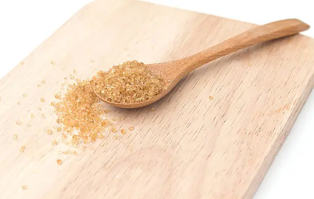 Heap of organic brown cane sugar with wooden spoon