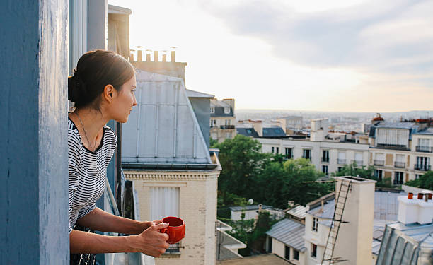 молодая женщина наслаждается на вид из на парижские апартаменты - paris france стоковые фото и изображения