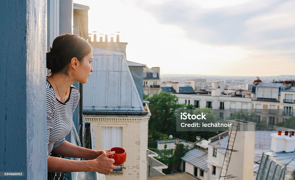 Young woman enjoying the view from a Parisian apartment - Royaltyfri Paris Bildbanksbilder