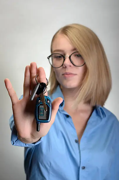 Woman with a car keys. Focus on keys. Isolated on grey background.