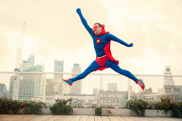 superhero jumping on city rooftop - superhero humor men cape imagens e fotografias de stock