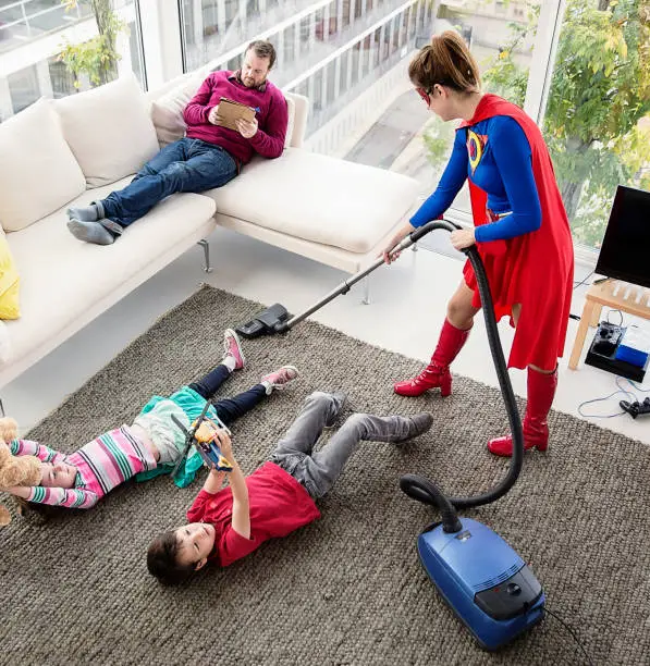Photo of Superhero vacuuming around family in living room