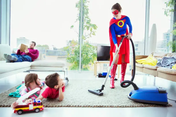 Photo of Superhero vacuuming around family in living room