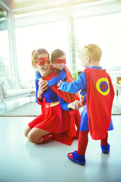 Photo of Superhero mother and children playing in living room