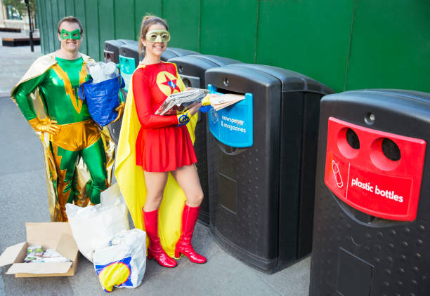 superheldenpaar-recycling auf dem bürgersteig der stadt - recycling green environment superhero stock-fotos und bilder