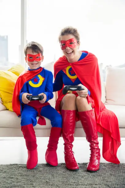 Photo of Superhero mother and son playing video game in living room