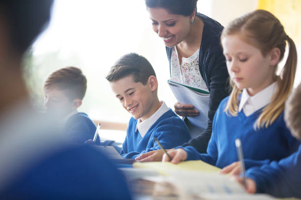 istock Smiling female teacher with his pupils in classroom 534575877