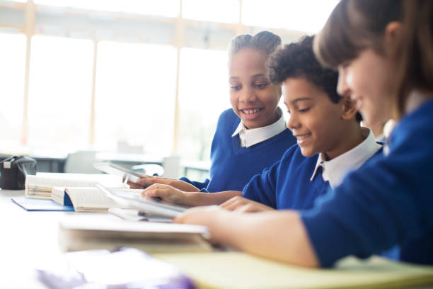 escolares y colegialas aprendiendo en el aula - uniforme de colegio fotografías e imágenes de stock