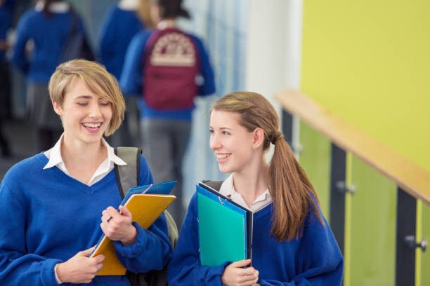 istock Two smiling female students wearing school uniforms walking through school corridor 534576011