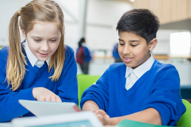 istock Boy and girl wearing school uniforms using digital tablet together 534576015