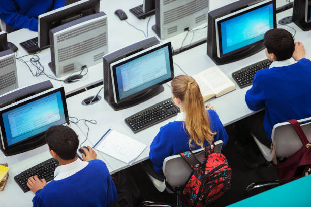 Rear view of lager group of people at a computer class. Teacher is teaching in the background.