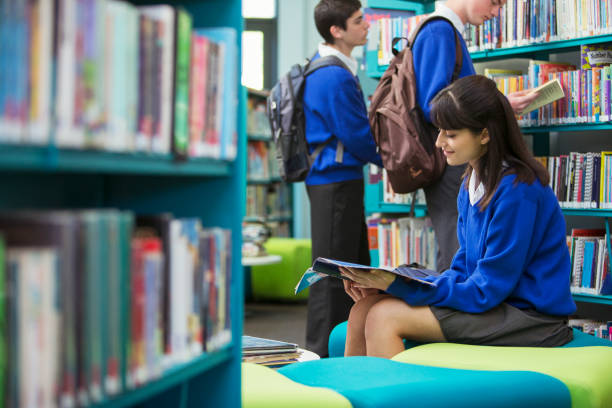 élèves lisant des livres à la bibliothèque - outer london photos et images de collection