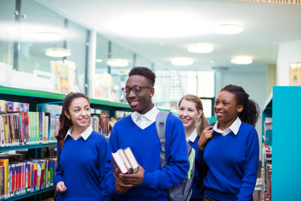 estudiantes alegres con uniformes escolares azules caminando por la biblioteca - student london england teenage girls teenager fotografías e imágenes de stock