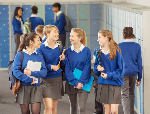 alegres alumnas vestidas con uniformes escolares azules caminando en el vestuario - uniforme fotografías e imágenes de stock