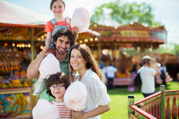 Portrait of cheerful family holding pink candy floss in amusement park  child cotton candy stock pictures, royalty-free photos & images