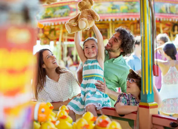 Photo of Girl holding teddy bear as trophy in fishing game in amusement park