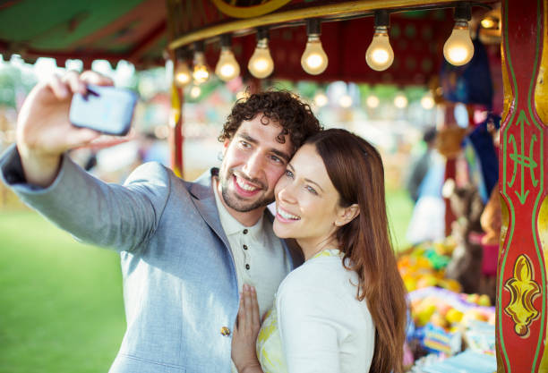 istock Smiling couple taking selfie in amusement park 534577069