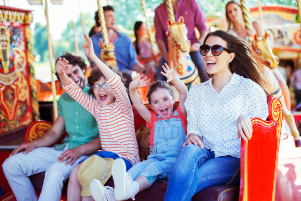 famille sur carrousel dans un parc d’attractions - attraction foraine équipement de loisirs photos et images de collection