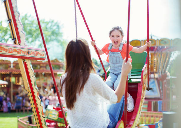 istock Mother and daughter playing on swing in amusement park 534577095