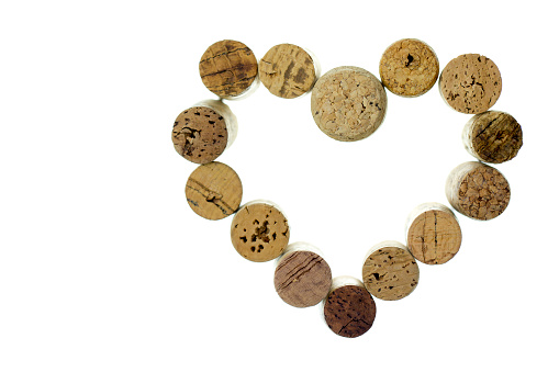 Stacks of one pound coins on a wooden table with Champagne cork and foil against a white background.