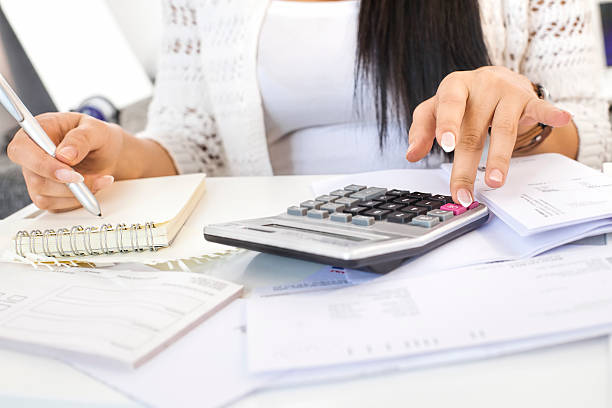 istock Woman's hand checks spreadsheet with calculator highlighters and pen 534603065
