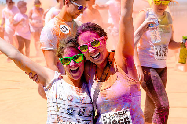 Toronto, Ontario, Canada - May 31, 2014: Two Female runners splattered with colourful powder smiling and cheering at the the Color Me Rad 5K Color Run on May 31, 2014 in Toronto, Ontario Canada. 