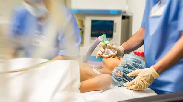 Blurred shot of little girl with oxygen mask lying on bed in operating room.