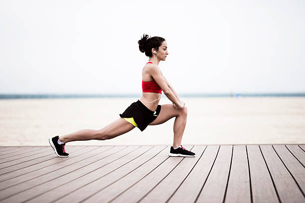 Morning exercise Young woman stretching on the beach, Dubai, Jumeirah Beach running shorts stock pictures, royalty-free photos & images