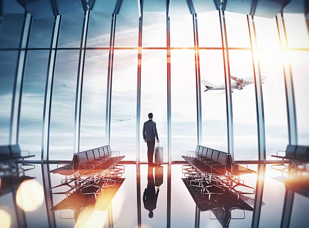 Businessman at airport near the window Man near panoramic window looking at the airplane business travel stock pictures, royalty-free photos & images