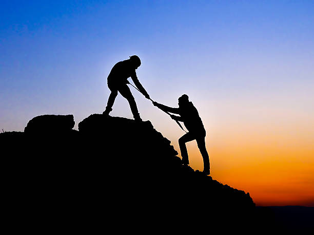 istock Silhouette of helping hand between two climber 534636831