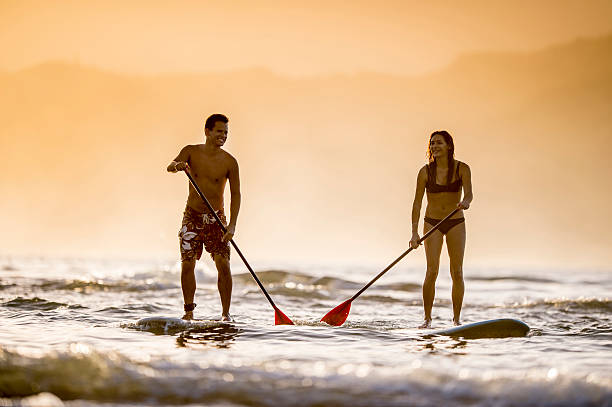 カップルのスタンドアップパドルボードスーペリア - women sensuality surfing water sport ストックフォトと画像