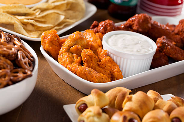 Party food A large party food spread with chicken fingers, hot wings, nachos with cheese dip, pretzels, pig in a blanket and beers.  Please see my portfolio for other food and drink images.  nacho chip photos stock pictures, royalty-free photos & images