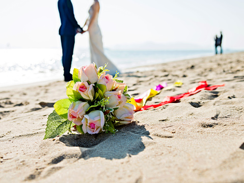 Wedding couple with bouquet on beach.