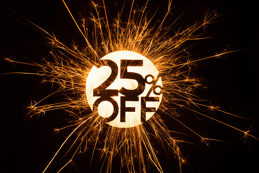 Circular 25 percent off sign in sparkling glowing design on dark background.