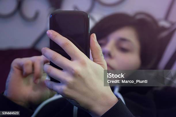 Chica Usa Smartphones A La Cama Foto de stock y más banco de imágenes de Mujeres - Mujeres, 2015, Adicción