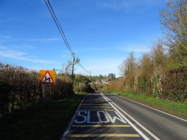 istock Bendy, winding road-sign triangle, white slow painted on road, yellow-lines 534665835