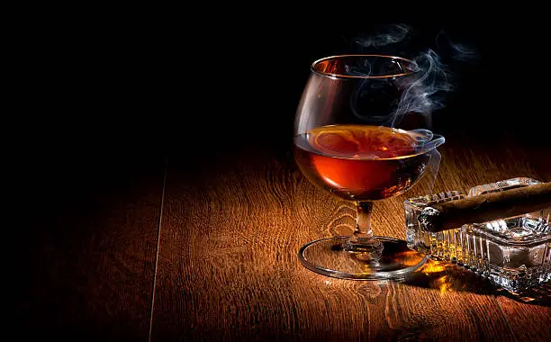 Cognac and cigar on ashtray on a wooden table