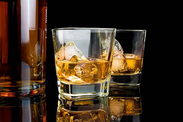 istock whiskey with ice in glasses near bottle on black background 534671094