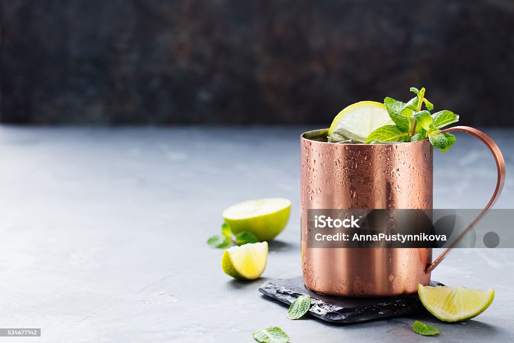 Cold Moscow Mules cocktail with ginger beer, vodka, lime Cold Moscow Mules cocktail with ginger beer, vodka, lime Grey stone background. Copy space Cocktail Stock Photo